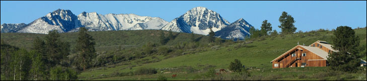 photo of large modern barn with snowy mountains behind